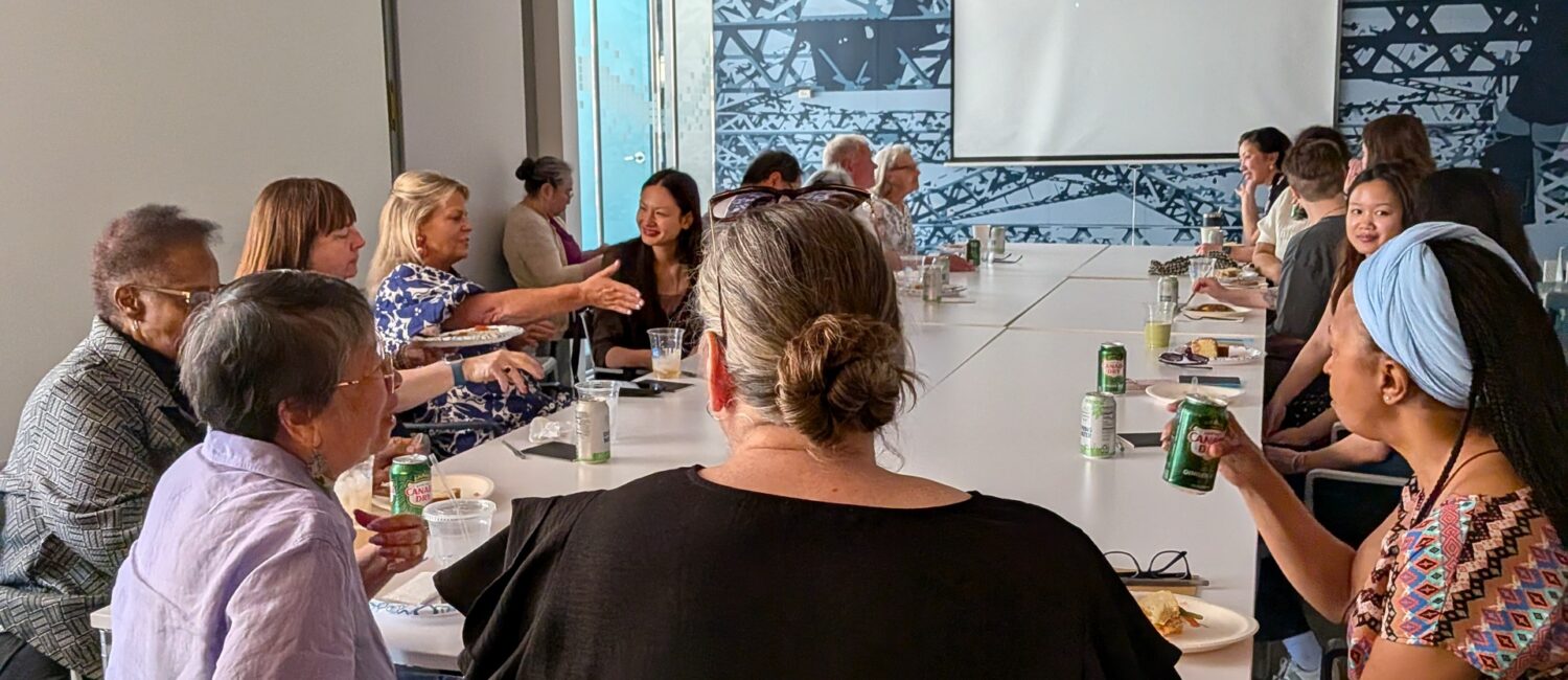 Attendees at Unerased film screening in Boston gather around the table enjoying food, each other's company, and having various discussions
