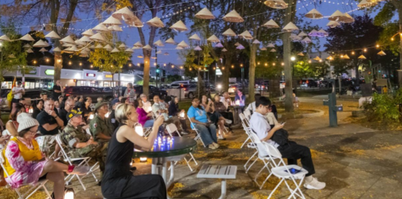 Audience sits outdoors in an open space decorated with nón lá and lights on top and in the background